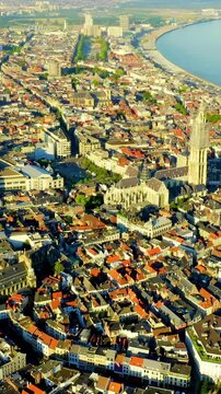 Vertical video. Antwerp, Belgium. The Cathedral of Our Lady, its 123-meter Brabantine Gothic spire rising above terracotta rooftops, Drone footage over the Scheldt river. Drone footage. Rich colors
