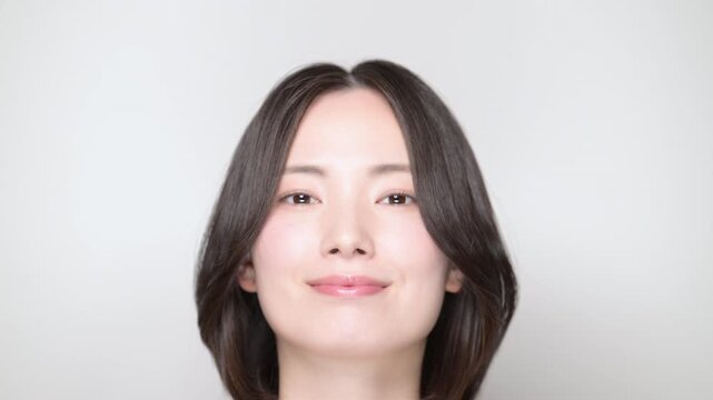下を向いて目を閉じてゆっくり正面で目を開く若い女性の美しい表情とナチュラルビューティーの動画　スキンケアなど