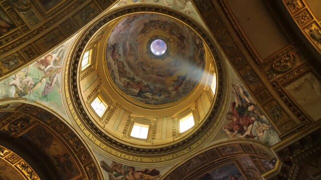 The grandeur of the interior of a historic Baroque or Renaissance church. The camera pans and tilts upwards to reveal the intricate and artistic details of the frescoes on the ceiling and dome.