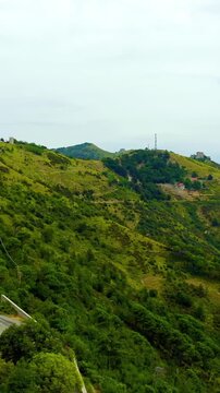Vertical video. Genoa, Italy. Forte Sperone, massive stone fortress crowning the forested ridge of the Mura Nuove, Drone footage over green hills toward the Ligurian coast.. Drone footage. Rich color