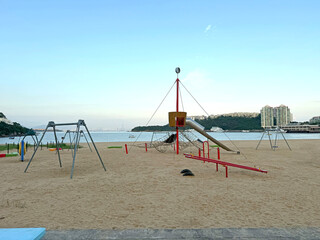 Fototapeta premium Beach playground with swings and slides overlooking the ocean and city skyline