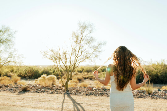 young woman waking in the desert in white dress
