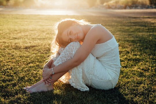 girl sitting curled up in the grass