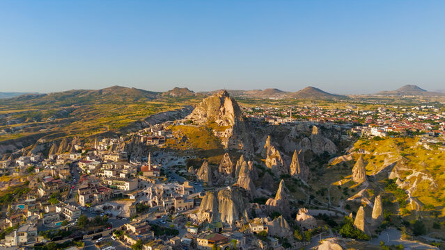 Uchisar, Nevsehir, Turkey. Uchisar Castle, a colossal rock-cut fortress rising from a volcanic tuff pinnacle, aerial view over the surrounding cave dwellings and fairy chimney landscape at golden hour
