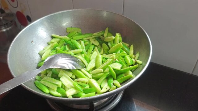 Saut&eacute;ing Sliced Ivy Gourd (Tindora) in a Wok on Gas Stove | Indian Cooking