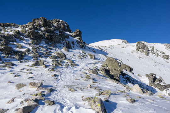 View of Slavkovsky nos peak covered in snow with jagged rocks under a clear blue sky in Vysoke Tatry, Presov Region, Slovakia.