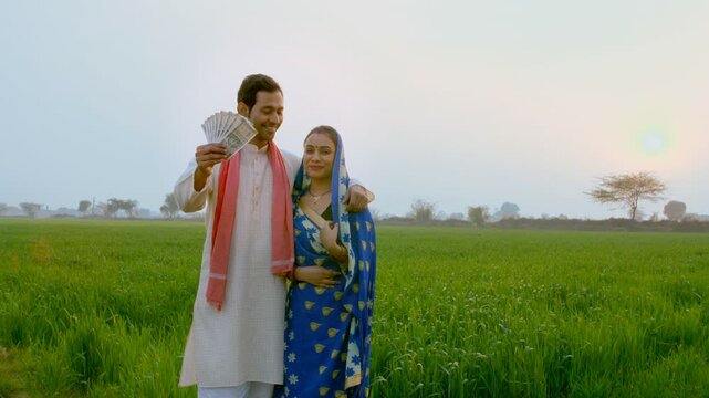 Village scene - Indian married couple happily showing their hard-earned money. Husband-wife holding five hundred rupee banknotes in their agricultural field - financial freedom  rich farmers