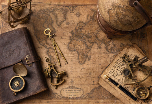 Vintage map on aged paper with antique navigation instruments like a brass sextant, compass, globe, and a fountain pen on a desk