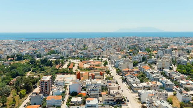 Alexandroupolis, Greece. Panoramic Drone footage over the central city and Thracian Sea coast, white apartment blocks and terracotta rooftops stretching toward a busy commercial port, clear summer sk
