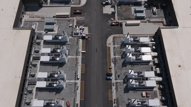 Aerial view of an industrial construction site with rows of white equipment units and heavy machinery