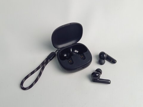Black wireless earphones with their case with white background isolation. Very effective and compact in its use