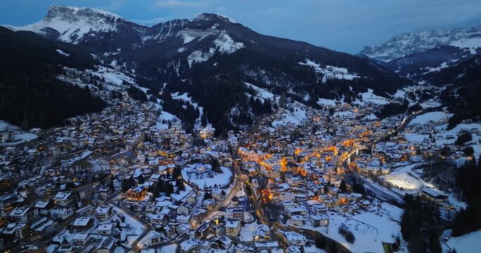 Winter panorama of Selva Val Gardena, snowy mountain town in the Dolomites, aerial footage.