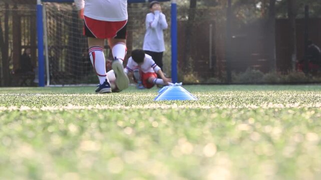 사람 축구 선수 스포츠 훈련 코트 야외 일상 소품 디테일 자재: 야외 인조잔디구장에서 유소년 선수가 고깔콘을 사이에 두고 볼 컨트롤 훈련을 하는 하체 중심의 로우앵글 동영상 클립입니다.