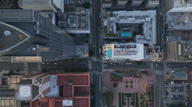Top down aerial of downtown Los Angeles revealing urban grid, tall skyscrapers, rooftop swimming pools, car traffic moving through city blocks and intersections