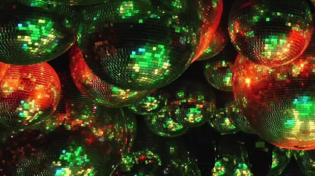 Witness mesmerizing spectacle of sparkling disco balls. Their faceted surfaces catch and scatter brilliant hues red, blue, purple, and green, painting captivating light show for joyous night gathering