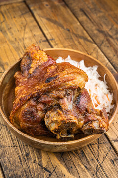 Bavarian style Schweinshaxe featuring maillard browned skin and tender meat paired with sauerkraut in a wooden bowl.