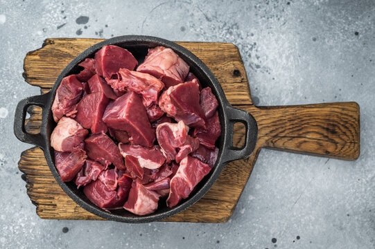 Diced lamb and goat hearts in a castiron skillet on a rustic board, perfect for hearty stews, braising and rich offal recipes.