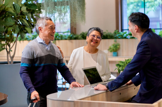 A couple of senior traveler check in at hotel with reception people.
