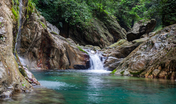 Sanzhanxi river in Taroko National Park. Scenic small waterfall flows into clear blue pool. Lush green forest surrounds rocky cliffs in Hualien, Taiwan.