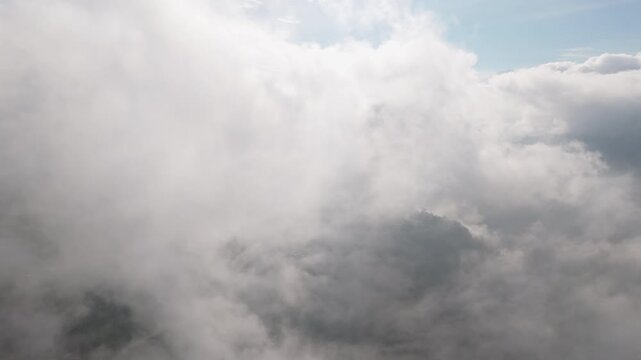 rone immersed within billowing, thick white cloud formations. Near-complete cloud coverage with only subtle sky visible at the top-right. No ground visible. 
