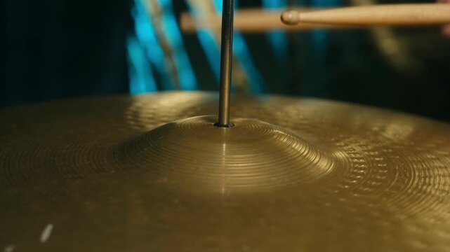 Close up drummer hitting ride cymbal with wooden drumstick, creating powerful vibrations and sound waves in music studio during performance or recording session. Drummer play ride cymbal drumstick
