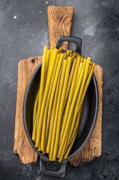 Pickled ramsons stems in cast iron cookware on wooden board dark food background natural plantbased ingredient