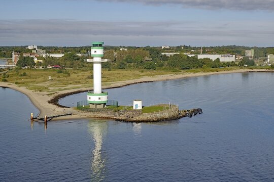 White-green lighthouse on a rocky coast with calm water and green landscape in the background, Kiel-Holtenau Lighthouse, Kiel Fjord, Kiel, Schleswig-Holstein, Germany