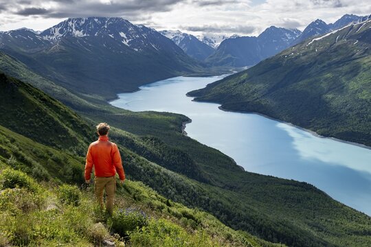 Mountaineer enjoys views of blue lake and mountains on Twin Peaks Trail, Eklutna Lake, Chugach Mountains, Chugach State Park, Alaska, USA