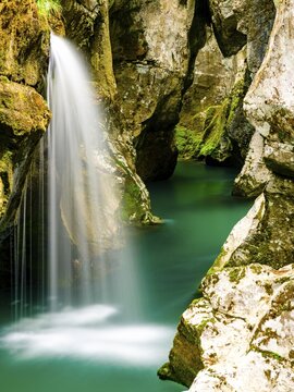 Waterfall plunges into the emerald green Soca River, Soca Valley, Triglav National Park, Bovec, Slovenia