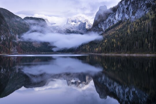 The Vordere Gosausee lake in autumn with a view of the Dachstein mountain range. The Gosaukamm on the right. Blue sky and clouds. In the evening after sunset. Reflection. Vorderer Gosausee, Gosau, Gosau valley, Salzkammergut, Upper Austria, Austria