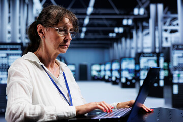 Fototapeta premium Elderly adept technician inside high tech facility providing computing resources needed for AI to process extensive datasets for training. Server hub storing data used for machine learning