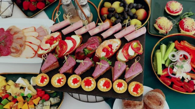 Gourmet appetizers arranged on multilevel serving stand, featuring canapes, bruschetta, mini tarts with complementing charcuterie, cheese, fresh seasonal fruits