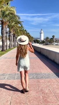 woman walking towards la farola lighthouse in malaga spain