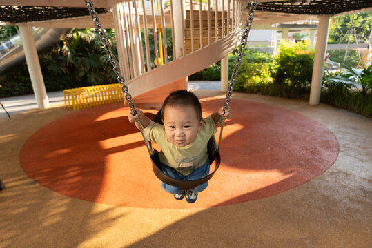 Little boy enjoying swing ride in sunny park