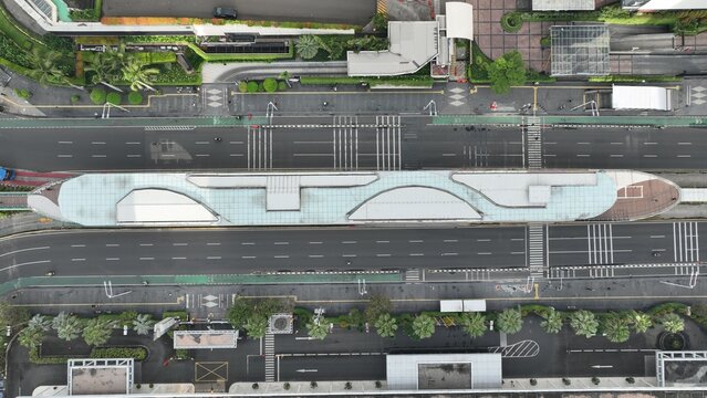 Menteng, Indonesia - 01 April 2025: Aerial view of the ship-shaped TransJakarta Bundaran HI bus station located between multi-lane city roads and pedestrian crossings.