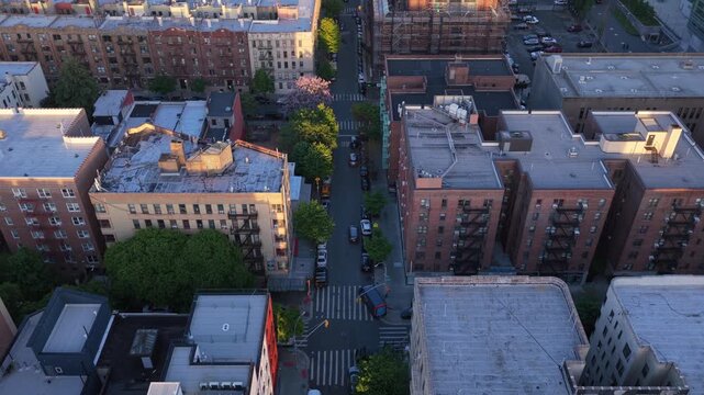 Golden sunset light illuminating urban apartment buildings and streets in South Bronx, New York, with cars driving through residential neighborhoods and morning city life
