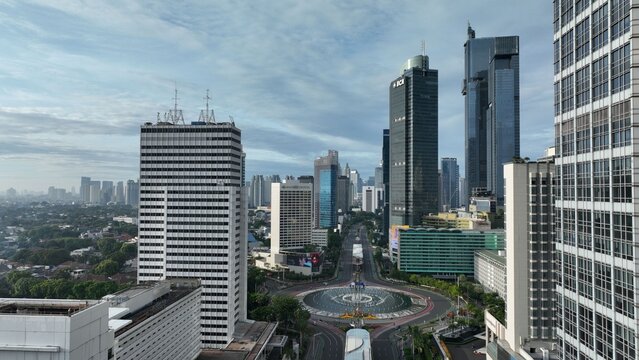 Menteng, Indonesia - 01 April 2025: Aerial view of Bundaran HI roundabout surrounded by modern skyscrapers, urban traffic routes, and dense city buildings under a cloudy sky.