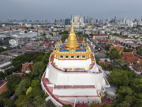 Bangkok, Thailand - 26 April 2026: Aerial view of Wat Saket Ratchawora Mahawihan, the Golden Mount, with its iconic golden chedi rising above the white base and city skyline.