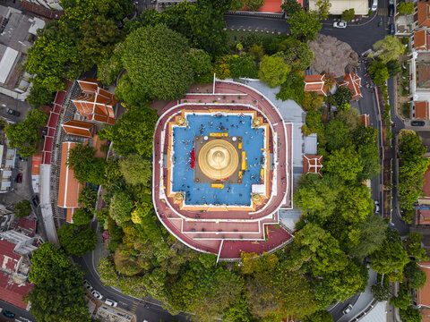 Bangkok, Thailand - 26 April 2026: Aerial view of Wat Saket Ratchawora Mahawihan, also known as the Golden Mount, with its golden chedi and blue platform surrounded by dense green trees.