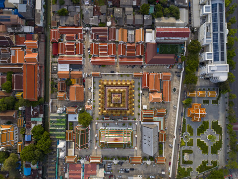 Bangkok, Thailand - 26 April 2026: Aerial view of the Loha Prasat at Wat Ratchanatdaram temple complex with its golden spires and traditional red-tiled rooftops under bright sunlight.
