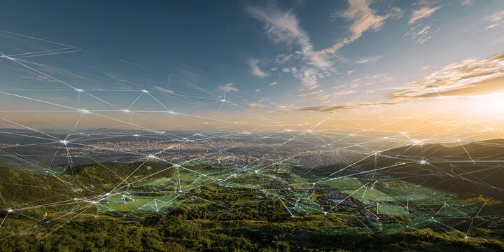 A scenic aerial view captures a sprawling city nestled amidst verdant hills and valleys under a vast, cloud-strewn sky at sunset