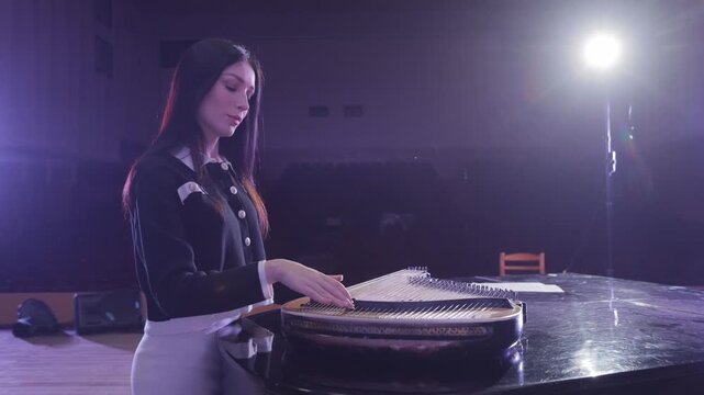 Young female musician playing qanun on stage
