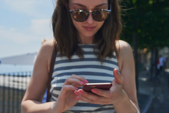 Phone, sunglasses and tourism with woman outdoor at coast to search digital map for location. App, shades and typing on mobile with tourist at beach for holiday, travel or vacation directions