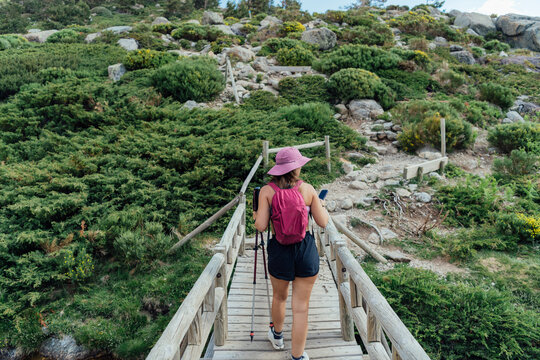 Woman with hiking poles crossing a wooden bridge
