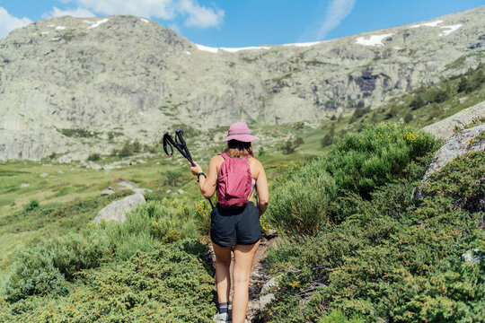 Woman with backpack hiking up a rocky mountain trail