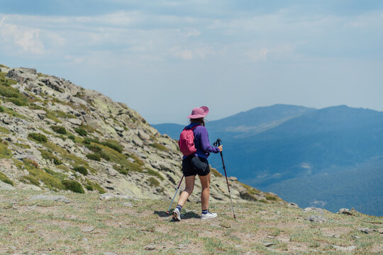 Woman with hiking poles walks along a mountain ridge