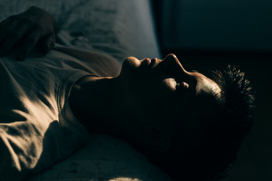 Young person lying down in bed with light on his face