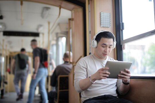 Young Asian man using a tablet on public transit