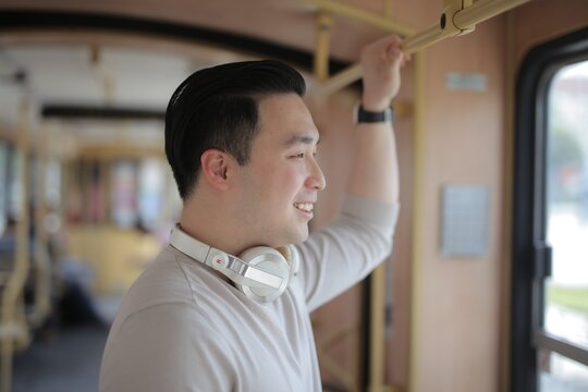 Smiling man with headphones looking out bus window