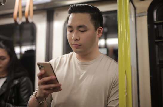 Young Asian man checking his phone on the subway